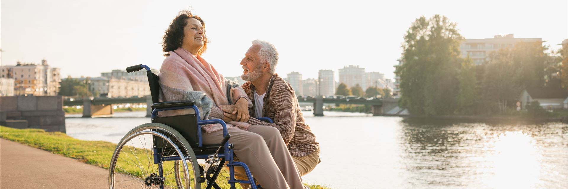 Frau im Rollstuhl genießt die Sonne bei Spaziergang mit Mann